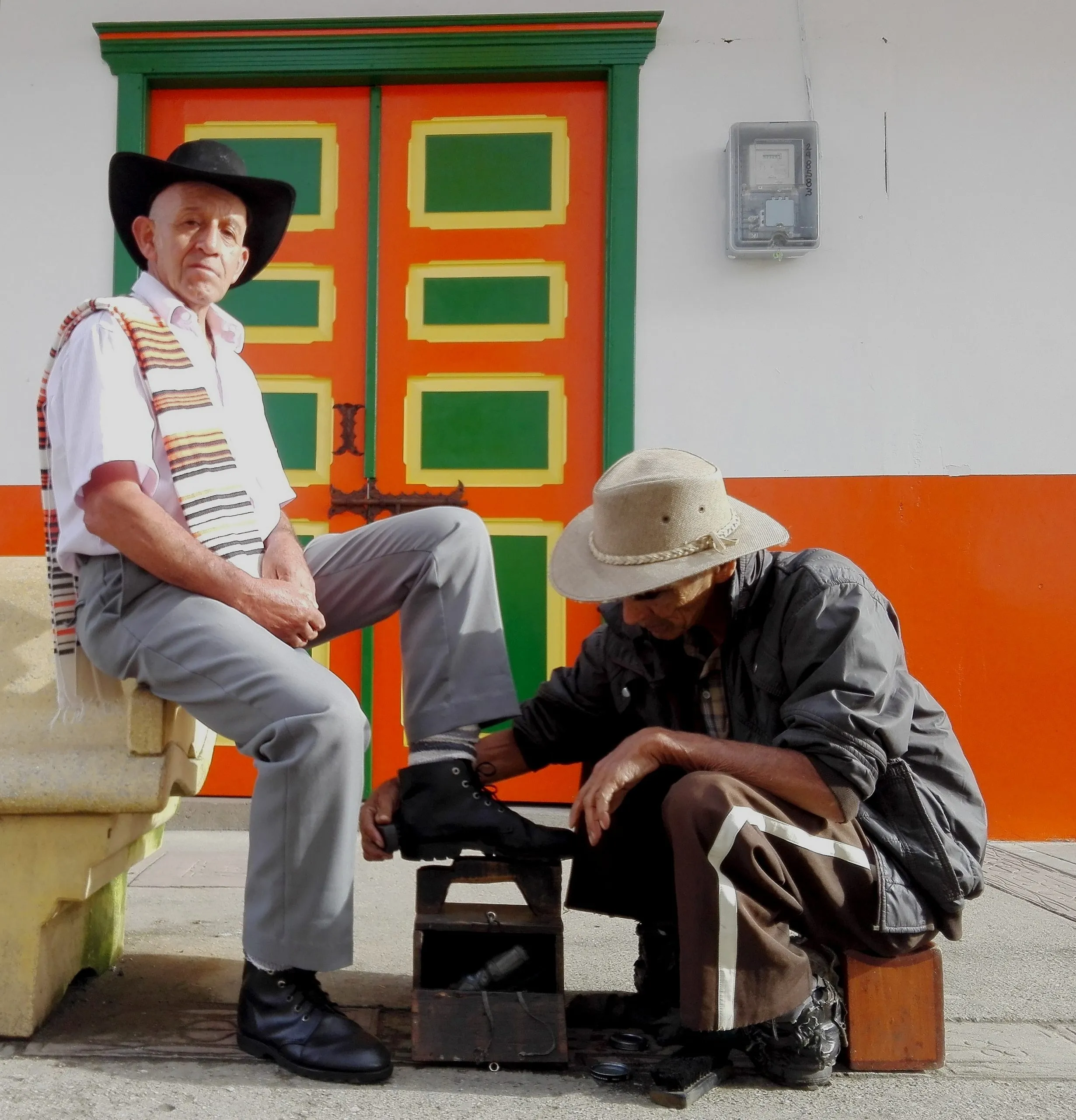 Homem de chapéu junto a uma porta colorida